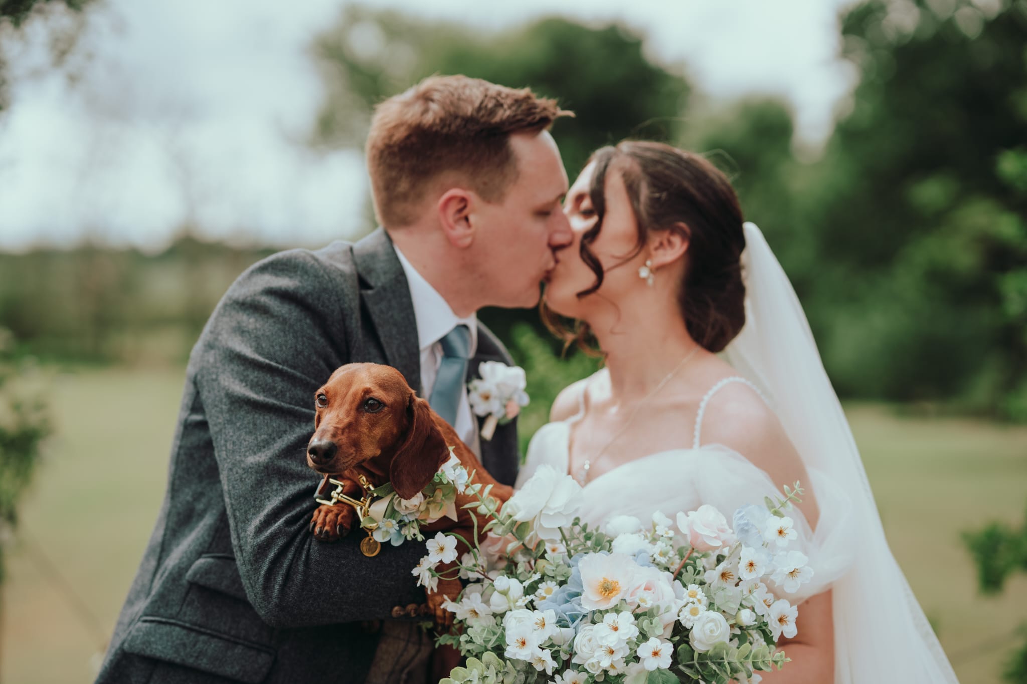 Couple sharing a kiss with their dog Beryl during a Waggy Wedding celebration, 2025