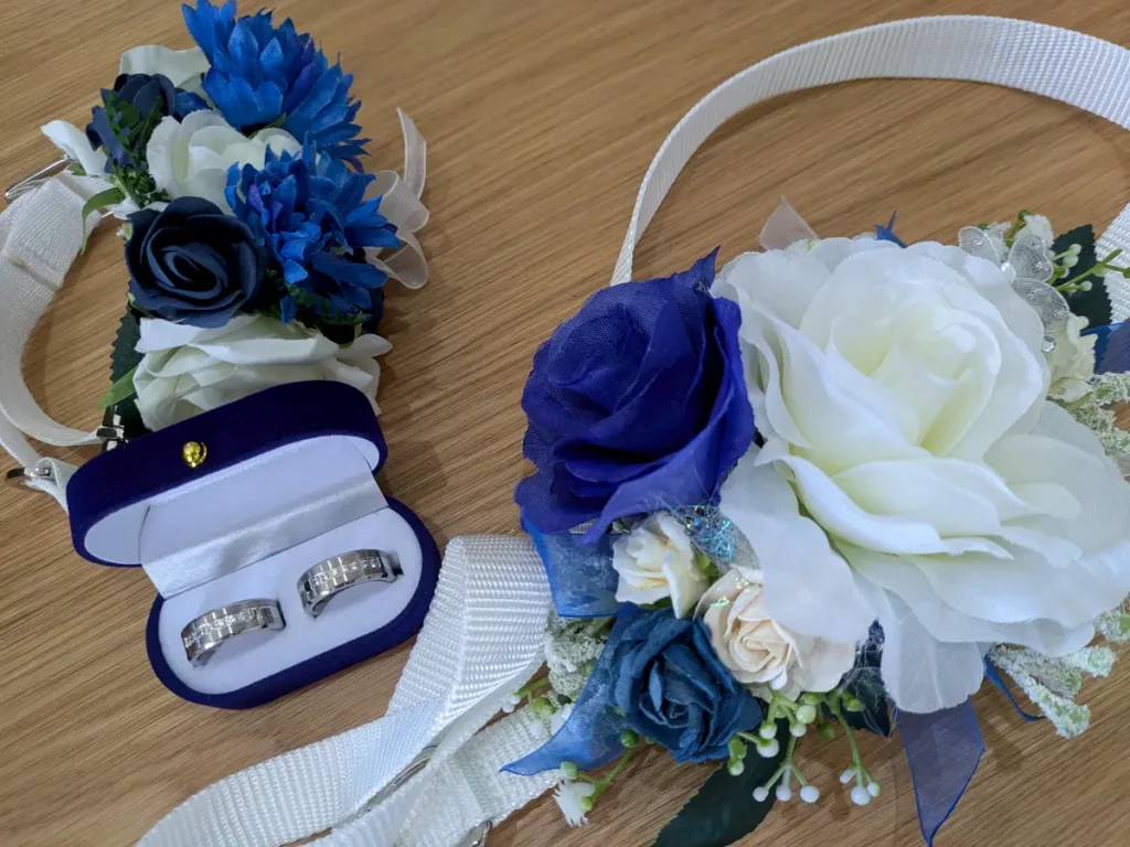 Wedding rings in blue velvet box alongside floral dog collar accessories for a dog ring bearer |
